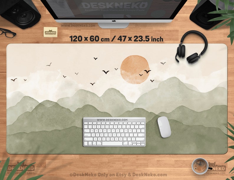 May include: A rectangular desk mat with a watercolor landscape design. The mat features a beige background with green mountains, a setting sun, and flying birds. The mat measures 47 x 23.5 inches.