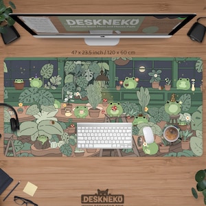 Puede incluir: Alfombrilla de escritorio estética con un diseño caprichoso de ranas y plantas. La alfombrilla mide 120 x 60 cm e incluye un teclado, un ratón y una taza de café. El logotipo de DESKNEKO está en la parte inferior.