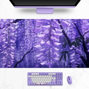 May include: A large, rectangular desk mat featuring a vibrant purple wisteria design. The image shows cascading purple flowers and green leaves. A matching keyboard, mouse, and headphones are also visible, creating a cohesive desk setup.