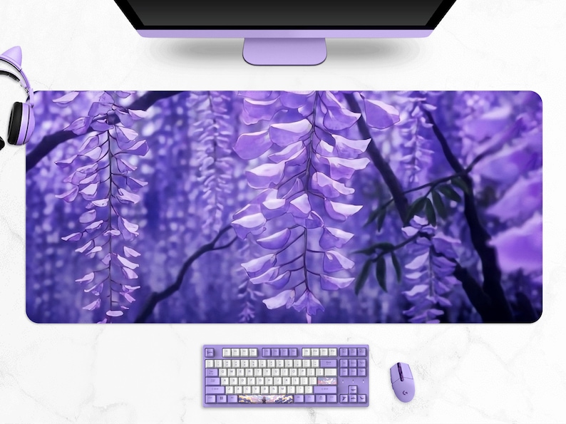 May include: A large, rectangular desk mat featuring a vibrant purple wisteria design. The image shows cascading purple flowers and green leaves. A matching keyboard, mouse, and headphones are also visible, creating a cohesive desk setup.