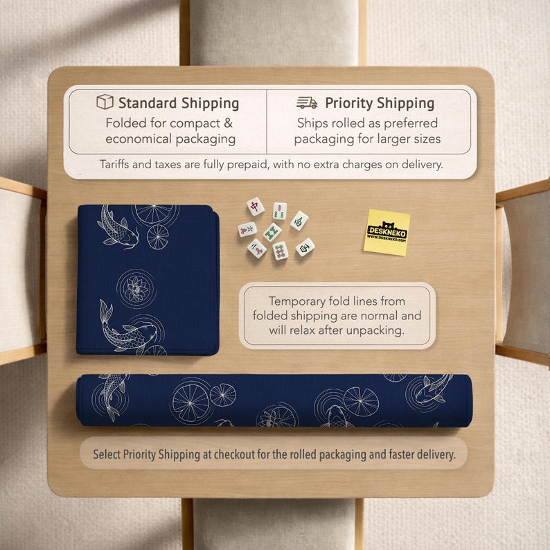 Puede incluir: Una alfombrilla de escritorio azul marino con un dise&ntilde;o de peces koi y nen&uacute;fares blancos, tanto plegada como enrollada. La imagen tambi&eacute;n muestra fichas de mahjong y una pegatina "DESKNEKO" sobre una superficie de madera.