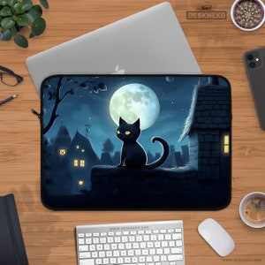 May include: Laptop sleeve featuring a black cat illustration set against a nighttime scene with a full moon and buildings. The sleeve has a black border and the text "DESKNEKO" is visible. The design is printed on a black surface.