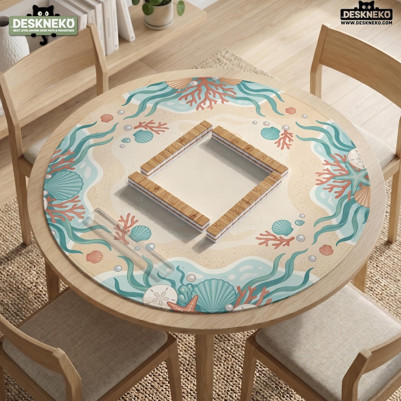 May include: A round desk mat featuring a beach-themed illustration with teal seaweed, orange coral, and various seashells on a sandy background. A square arrangement of wooden mahjong tiles sits in the center. The DESKNEKO logo is visible.