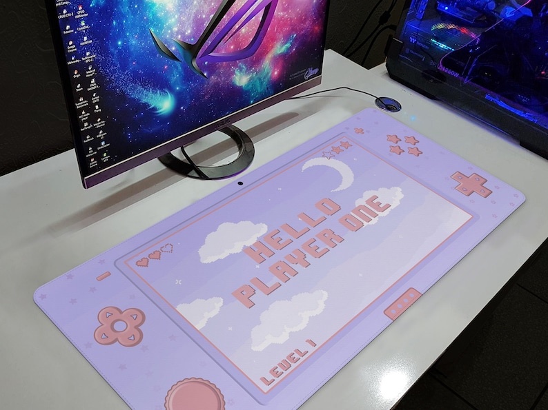 K&ouml;nnte beinhalten: Ein lila Gaming-Mauspad mit Pastell-Design. Das Pad zeigt den Text "HELLO PLAYER ONE" mit Wolken, Sternen und einem Mond. Es hat ein vom Controller inspiriertes Design mit rosa Akzenten und dem Text "LEVEL 1".