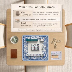 May include: A Mahjong set with a blue and white patterned mat, tiles, a small bowl of green marbles, a brown notebook, and wooden letter tiles spelling Neko Desk. An informational sign displays Mini Sizes For Solo Games with 15.7 inch and 20.9 inch labels.
