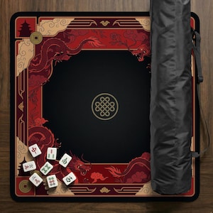 May include: A black Mahjong mat with a red and gold dragon design. The mat has a black center with a gold knot symbol. Several white Mahjong tiles are scattered on the mat. A black carrying case is on the right.