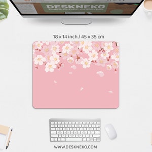 May include: Pink mouse pad, 18 x 14 inches, with a floral cherry blossom design. The blossoms are white and pink, with falling petals. The website address www.deskneko.com is printed at the bottom.