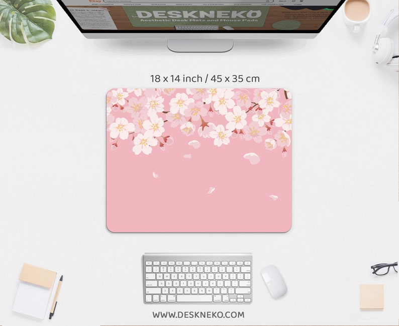 May include: Pink mouse pad, 18 x 14 inches, with a floral cherry blossom design. The blossoms are white and pink, with falling petals. The website address www.deskneko.com is printed at the bottom.