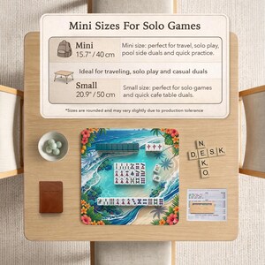May include: A Mahjong set on a tropical beach-themed playmat with a printed informational sign titled Mini Sizes For Solo Games, listing dimensions of 15.7 inches and 20.9 inches, alongside a small bowl of marbles, a brown notebook, and wooden letter tiles.