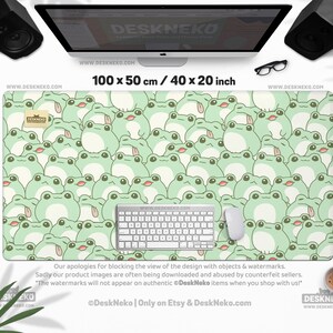 May include: A large desk mat featuring a repeating pattern of light green cartoon frogs. The mat is 40 inches long and 20 inches wide, with a white keyboard and mouse on top. The text "DESKNEKO" and "www.DESKNEKO.COM" are visible.