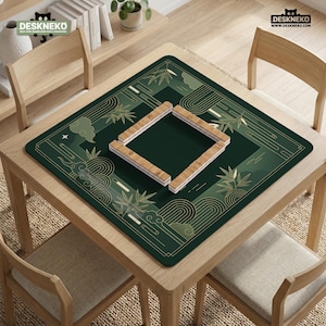 Pode incluir: Uma mesa quadrada de madeira com um tapete verde e dourado estampado, com desenhos de bambu e nuvens. O tapete tem um recorte quadrado com pe&ccedil;as de jogo de madeira no interior. A mesa &eacute; rodeada por quatro cadeiras de madeira. O texto "DESKNEKO" &eacute; vis&iacute;vel.