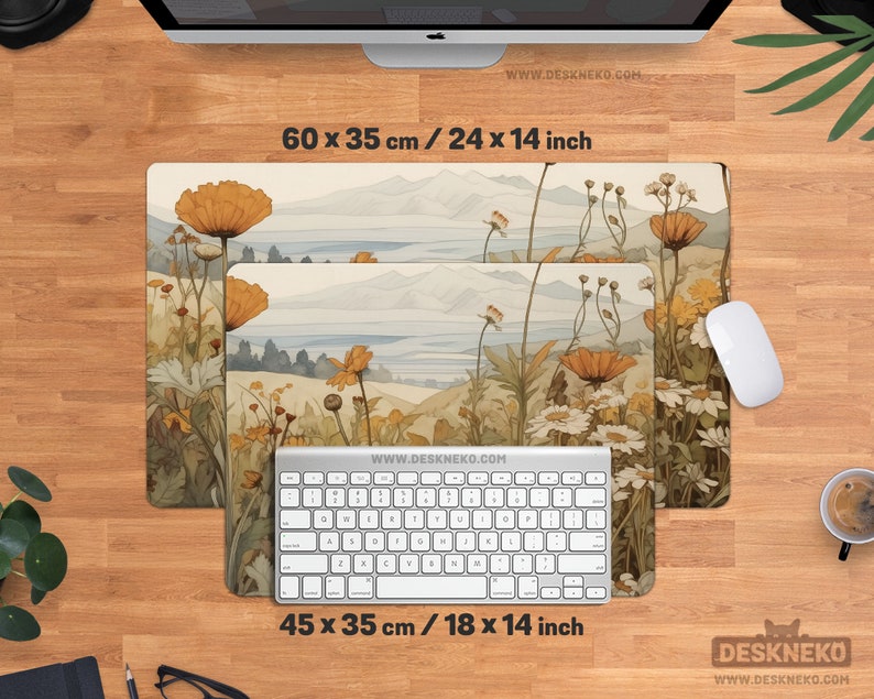 May include: Two rectangular desk mats featuring a floral landscape design. The larger mat measures 60 x 35 cm, and the smaller one is 45 x 35 cm. A white keyboard and mouse are on the wooden desk. The website address is visible.