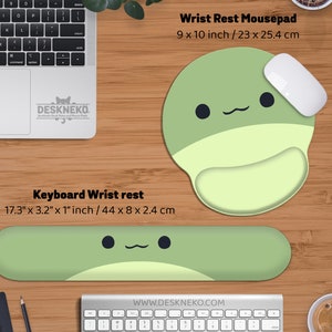 May include: A green and light green wrist rest mousepad, 9 x 10 inches, and a keyboard wrist rest, 17.3 x 3.2 x 1 inches, with a cute cartoon face design. A white mouse rests on the mousepad. The brand name is Deskneko.