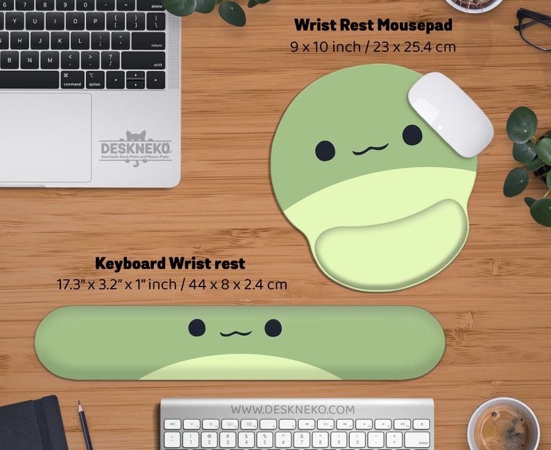 May include: A green and light green wrist rest mousepad, 9 x 10 inches, and a keyboard wrist rest, 17.3 x 3.2 x 1 inches, with a cute cartoon face design. A white mouse rests on the mousepad. The brand name is Deskneko.