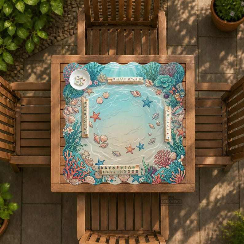 May include: A square wooden table with a decorative mat featuring an ocean scene with seashells, starfish, and coral. The mat has a light blue and beige colour scheme. Two wooden chairs are on either side of the table. A small white bowl is on the table.