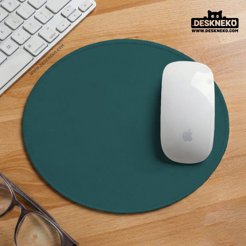 May include: A teal green round mouse pad with a white computer mouse and keyboard. The mouse pad has a stitched edge. The website address www.deskneko.com is visible on the mouse pad and in the upper right corner.