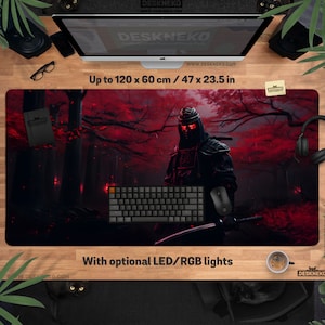 May include: A large rectangular desk mat with a ninja warrior in a red forest design. The mat measures up to 120 x 60 cm (47 x 23.5 in) and has the text "Up to 120 x 60 cm / 47 x 23.5 in" and "With optional LED/RGB lights". A keyboard, mouse, and other accessories are on the mat.