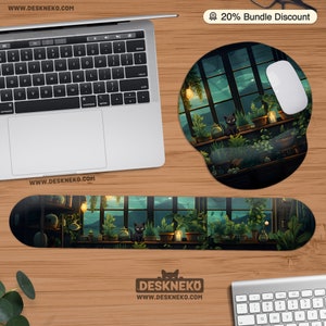 Op de afbeelding: Een muismat en polssteun set met een illustratie van een kas en een zwarte kat. Het ontwerp bevat planten, kaarsen en een nachthemel. De set staat op een houten bureau met een laptop.