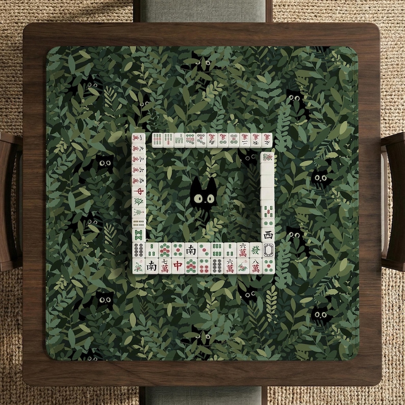 May include: A square mahjong table with a green leaf pattern and black cat silhouettes. The center features a square of white mahjong tiles. The table is made of dark wood.