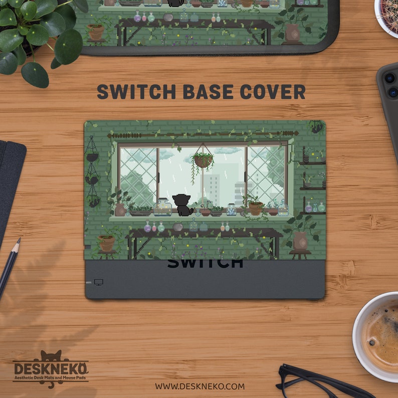 May include: A rectangular Switch base cover with a pixelated illustration of a cat gazing out of a window on a rainy day. The cover has a green brick wall design with plants and the word "SWITCH" printed on it.
