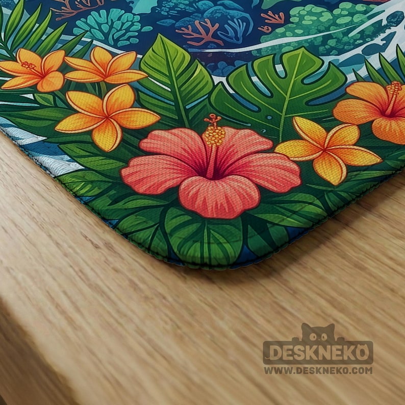 May include: A vibrant desk mat featuring a tropical floral design. The mat showcases a large pink hibiscus flower, orange flowers, and green leaves against a blue and teal background. The mat has the text "DESKNEKO" and the website address.