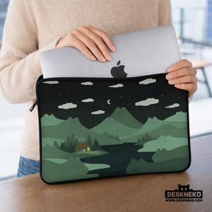 May include: A black laptop sleeve featuring a scenic illustration of a night landscape with mountains, a river, and a cabin with a lit window. The design includes clouds, stars, and a crescent moon. The sleeve is holding a silver laptop.