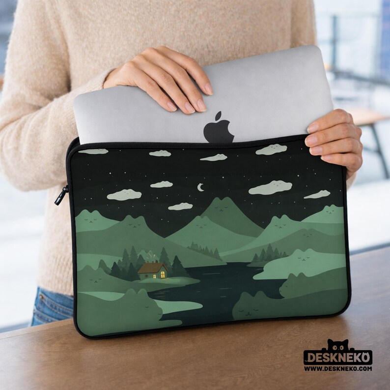 May include: A black laptop sleeve featuring a scenic illustration of a night landscape with mountains, a river, and a cabin with a lit window. The design includes clouds, stars, and a crescent moon. The sleeve is holding a silver laptop.