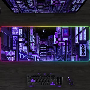 May include: A rectangular gaming mouse pad with a pixelated cityscape design in shades of purple and blue, with the word "TOKYO" visible. The pad has a glowing, multi-colored edge. A keyboard and mouse are below.