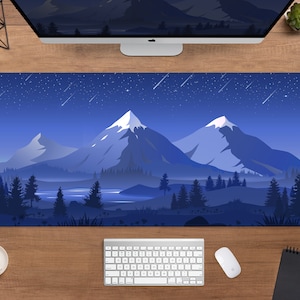May include: A rectangular desk mat featuring a mountain landscape under a starry night sky. The design includes snow-capped peaks, a forest, and a lake, all in shades of blue. A keyboard, mouse, and coffee cup are visible.