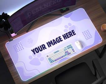 Może przedstawiać: Prostokątna, jasnofioletowa podkładka pod mysz do gier z motywem łap i napisem "YOUR IMAGE HERE". Biała klawiatura i mysz znajdują się na podkładce. Podkładka ma świecącą krawędź i leży na drewnianym biurku.