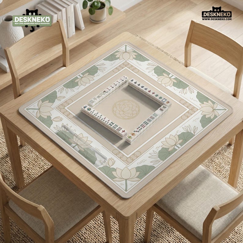 May include: A square wooden table with a beige mahjong mat featuring a lotus flower design. A set of mahjong tiles is arranged on the mat. The table is surrounded by four wooden chairs. The logo "DESKNEKO" is visible in the top left and right corners.