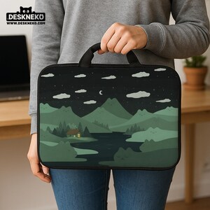 May include: A black laptop sleeve with a handle featuring a landscape design. The design includes a night sky with clouds and a crescent moon, mountains, a river, and a cabin with a lit window. The brand name "DESKNEKO" is at the top.