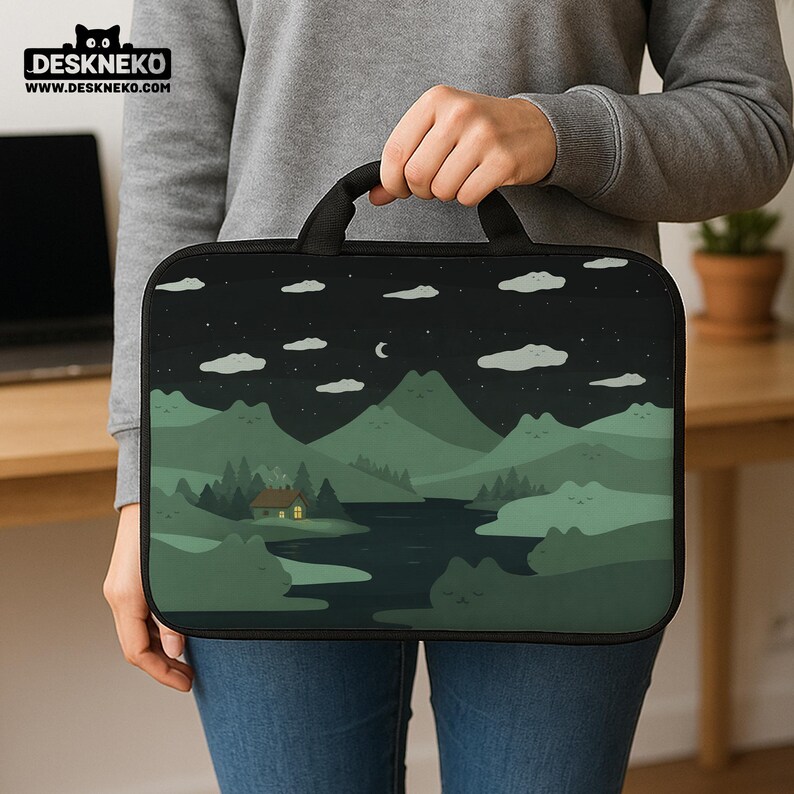 May include: A black laptop sleeve with a handle featuring a landscape design. The design includes a night sky with clouds and a crescent moon, mountains, a river, and a cabin with a lit window. The brand name "DESKNEKO" is at the top.