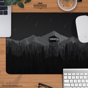 May include: Black and gray desk mat featuring a mountain scene with a fire tower, trees, and shooting stars. The mat has the text "DESKNEKO" and "WWW.DESKNEKO.COM".