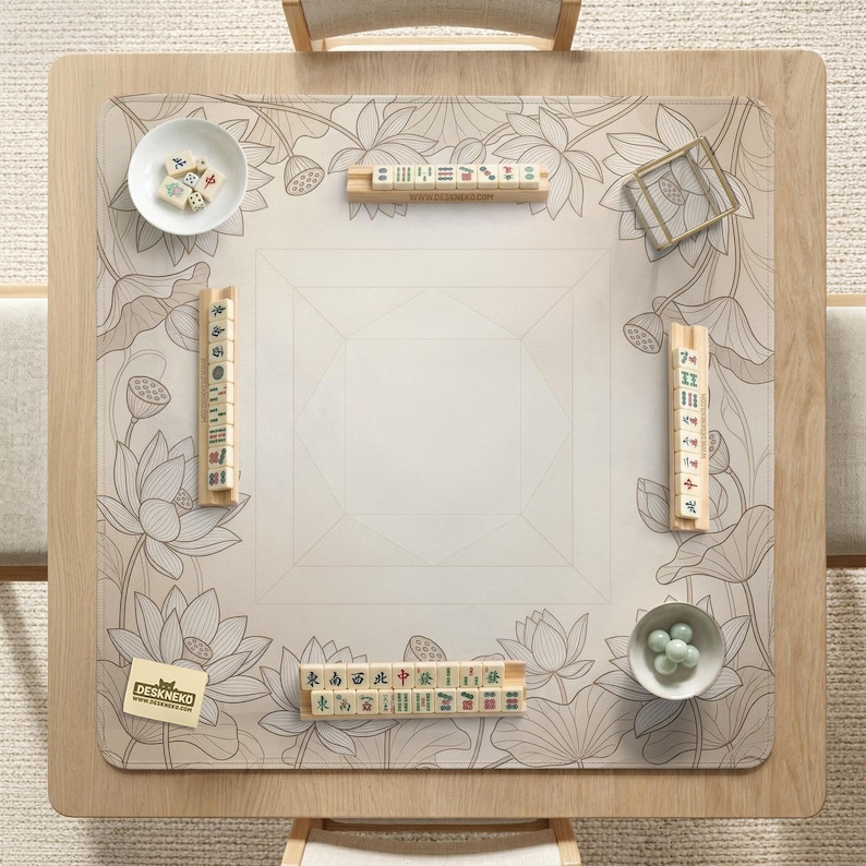 Puede incluir: Una mesa de mahjong cuadrada de madera con una estera de dise&ntilde;o floral. La estera presenta un patr&oacute;n de flor de loto en tonos grises. Las fichas y accesorios de mahjong est&aacute;n dispuestos sobre la mesa, incluyendo dados y cuencos peque&ntilde;os. La mesa est&aacute; lista para un juego.