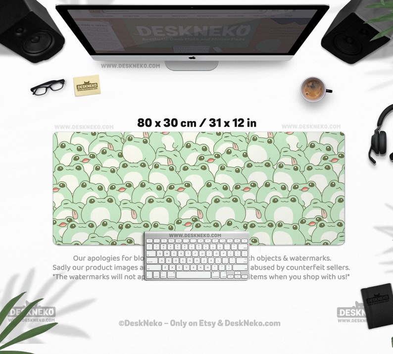 May include: A rectangular desk mat, 31 x 12 inches, featuring a repeating pattern of light green cartoon frogs on a pale green background. A white keyboard sits on the mat. The website address www.deskneko.com is visible.