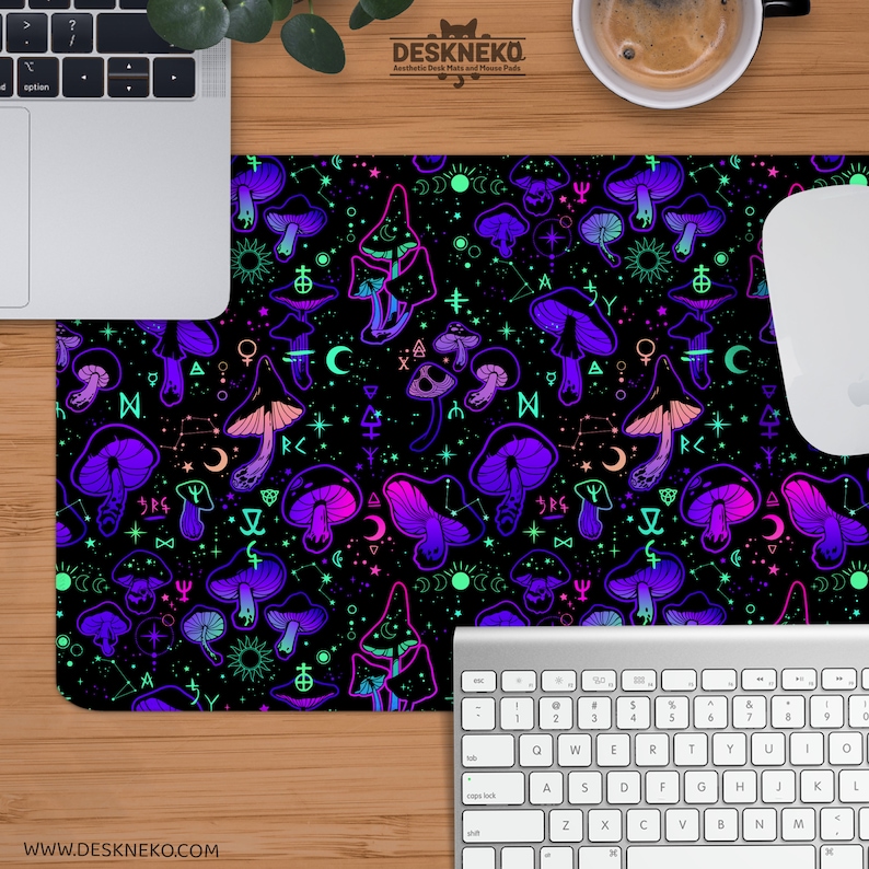 May include: Black desk mat with a repeating pattern of neon purple, pink, and green mushrooms and celestial symbols. The mat has the text "DESKNEKO" and "WWW.DESKNEKO.COM". A laptop, keyboard, and mouse are visible.