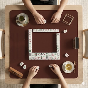 May include: A white ceramic mug with a black handle and the text "But First, Coffee" in a bold, black font. The mug is set against a blurred background, suggesting a cozy setting.