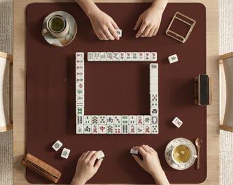 以下が含まれることがあります： 黒い持ち手と「But First, Coffee」の太字の黒い文字が入った白いセラミックマグカップ。マグカップはぼやけた背景に置かれており、居心地の良い環境を示唆しています。