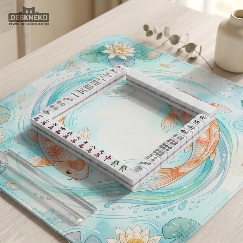 K&ouml;nnte beinhalten: Eine quadratische Schreibtischunterlage mit einer hellblauen und wei&szlig;en Illustration von Koi-Fischen und Lotusblumen, auf der rechteckig angeordnete wei&szlig;e Mahjong-Steine liegen. Die Unterlage enth&auml;lt den Text DESKNEKO und WWW.DESKNEKO.COM.