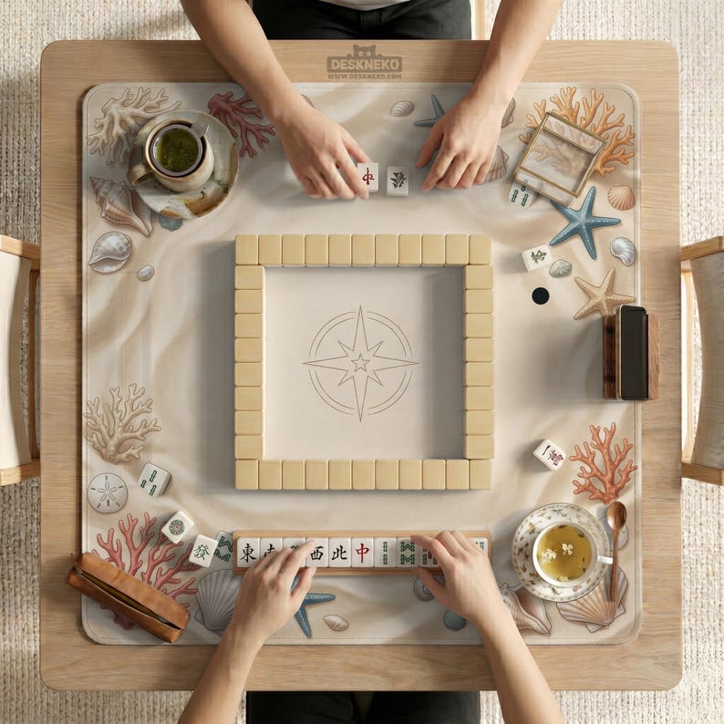 以下が含まれることがあります： 木製の麻雀ゲームテーブル。ベージュ色のプレイ面にはコンパスのデザインが施されています。テーブルには牌、サイコロ、ティーカップがセットされています。テーブルの上部には「DESKNEKO」の文字があります。
