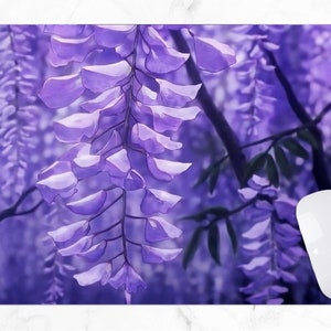 May include: A rectangular mousepad featuring a watercolor-style image of cascading purple wisteria flowers. A white Apple mouse is positioned on the right side of the mousepad, providing a contrast to the floral design.