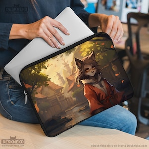May include: Black laptop sleeve featuring a detailed anime-style illustration of a fox-like character in a red robe, set against a backdrop of traditional Japanese buildings. The sleeve has a black zipper and trim, with the "DeskNeko" logo visible.
