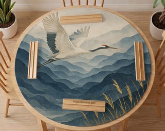 May include: A round desk mat featuring a white crane in flight over layered blue mountains. The design includes golden wheat stalks in the foreground and four light wood rectangular stands placed on the mat. The text WWW.DESKNEKO.COM is visible.