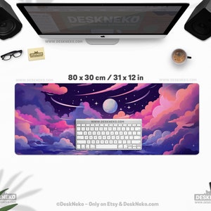 Pu&ograve; includere: Un tappetino per scrivania rettangolare con un design a cielo notturno da sogno. Il tappetino misura 80 x 30 cm e presenta una vivace illustrazione di nuvole rosa e viola, una luna piena e stelle. Una tastiera bianca &egrave; sopra.