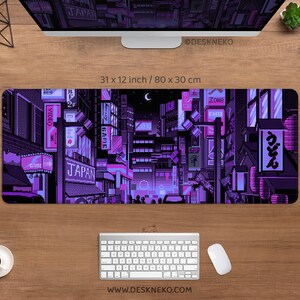 K&ouml;nnte beinhalten: Eine Schreibtischunterlage mit einem pixeligen Stadtbild in Lila und Pink, mit japanischen Schriftzeichen. Die Matte misst 80 x 30 cm. Das Design enth&auml;lt die W&ouml;rter "JAPAN" und "GAME". Die Website-Adresse "WWW.DESKNEKO.COM" ist ebenfalls sichtbar.