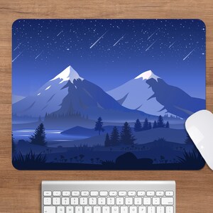 May include: A rectangular mousepad featuring a nighttime mountain landscape with a starry sky and shooting stars. The design is predominantly blue with white accents. A white computer mouse and keyboard are also visible.