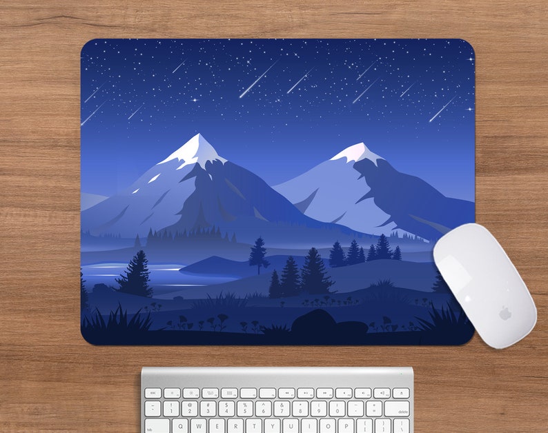 May include: A rectangular mousepad featuring a nighttime mountain landscape with a starry sky and shooting stars. The design is predominantly blue with white accents. A white computer mouse and keyboard are also visible.