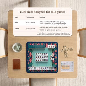 May include: A tabletop display featuring a mini Mahjong set with a teal playing surface and flamingo and floral design. The set includes tiles, dice, and a small brown notebook. The text on the display reads "Mini sizes designed for solo games."