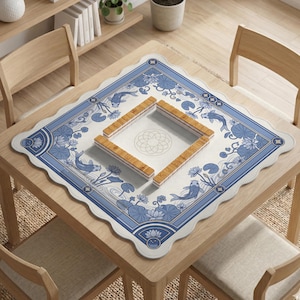 May include: A square, light-colored wooden table with a blue and white patterned Mahjong mat. The mat features koi fish, lotus flowers, and a decorative border. Four wooden Mahjong tile racks are arranged on the mat.